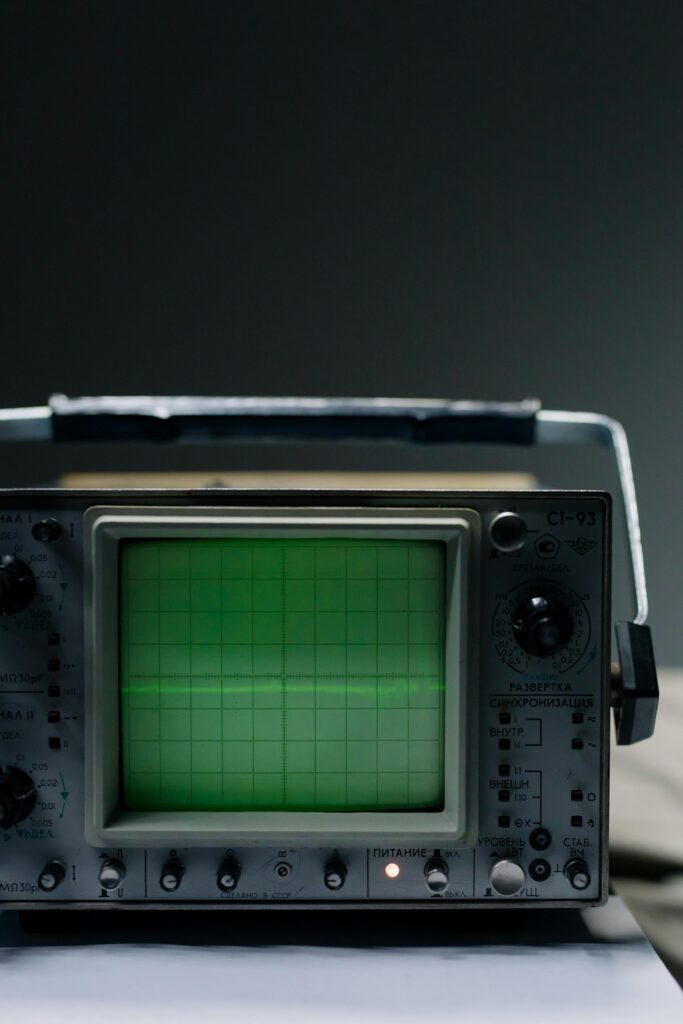 Close-up of a vintage oscilloscope showing a green waveform on a grid screen.
